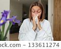Seasonal allergy. Close up face of allergic young woman uses paper tissues from runny nose, sneezes from flowers pollen at home. Girl with close eyes with flu, itching or cough, allergy rhinitis 133611274