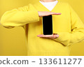 Mobile App advertisement. unrecognisable woman shows black empty smartphone screen over yellow background. Cellphone display mock up. Online service marketing, digital product promotion 133611277