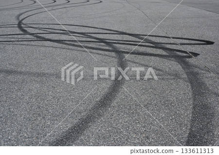 an asphalt surface covered in overlapping tire skid marks from high-speed driving maneuvers such as drifting or burnouts an asphalt surface covered in overlapping tire skid marks from high-speed driving maneuvers such as drifting or burnouts 133611313