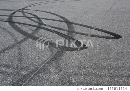 an asphalt surface covered in overlapping tire skid marks from high-speed driving maneuvers such as drifting or burnouts an asphalt surface covered in overlapping tire skid marks from high-speed driving maneuvers such as drifting or burnouts 133611314