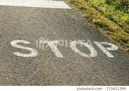 The text STOP is written in white paint on the asphalt near the curb 133611366