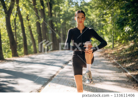 Legs warm up. Young sportive skinny woman is in black fitness clothes outdoors 133611406