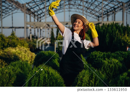 Making a selfie. Young redhead woman is taking care of garden 133611950