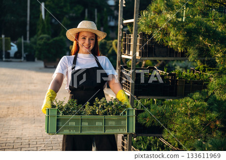 Young redhead woman is taking care of garden Young redhead woman is taking care of garden 133611969