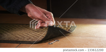 A person getting a key from under their mat A person getting a key from under their mat 133612200