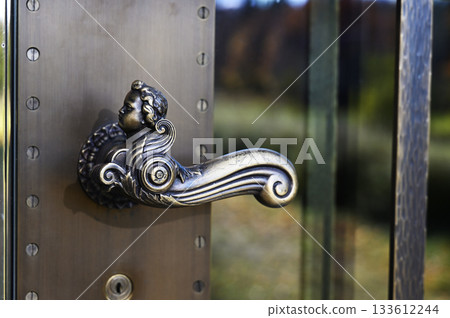 an ornate bronze door handle shaped like a cherub or angel figure 133612244