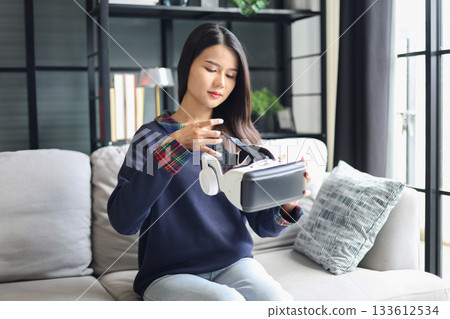 Young asian woman wearing virtual reality glasses. VR headset. VR concept. Young asian woman wearing virtual reality glasses. VR headset. VR concept. 133612534