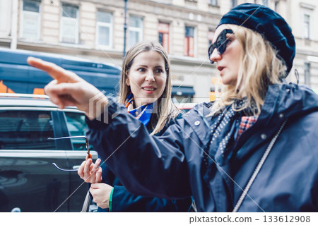 Two female friends are walking through city streets and looking at shop windows 133612908