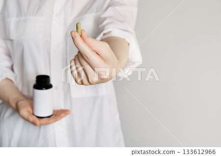Woman holding green natural capsule and blank label vitamin bottle, Copy space Woman holding green natural capsule and blank label vitamin bottle, Copy space 133612966