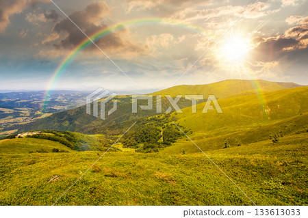 alpine meadows in mountains in summer at sunset. beautiful view of rolling hills with lush green grass under blue sky in evening light. travel destination storytelling image under the rainbow 133613033