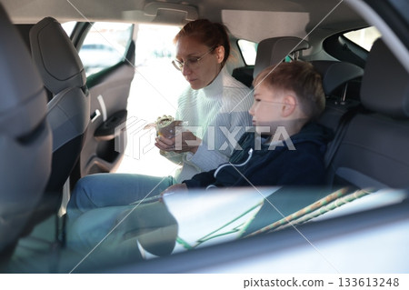 Mother and son sharing snack inside car 133613248