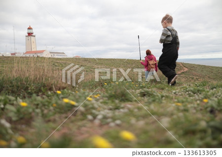 Family exploring coastal landscape path with lighthouse Family exploring coastal landscape path with lighthouse 133613305
