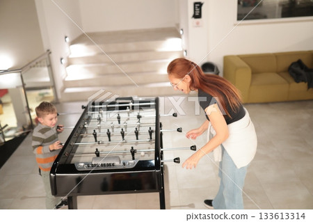 Mother and child playing foosball together indoors Mother and child playing foosball together indoors 133613314