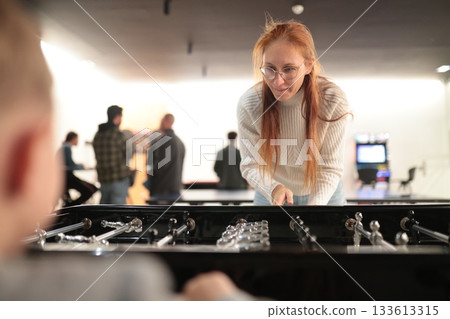 Woman playing foosball concentrating on the game Woman playing foosball concentrating on the game 133613315