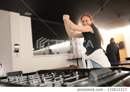 Woman celebrating victory playing foosball game Woman celebrating victory playing foosball game 133613317