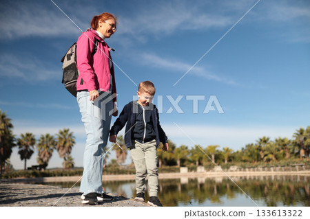 Woman and boy exploring lake with palm trees Woman and boy exploring lake with palm trees 133613322