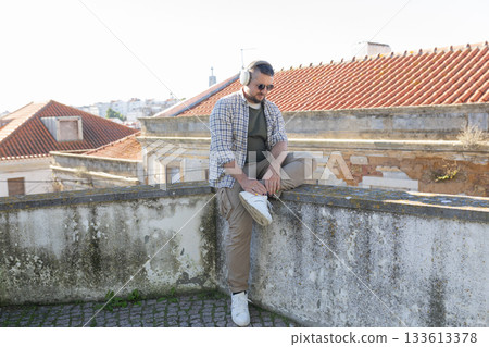 Man relaxing urban environment listening music headphones Man relaxing urban environment listening music headphones 133613378
