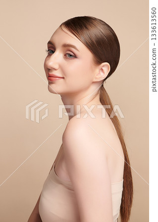 A beautiful young woman with clean, fresh skin against a beige background. Skincare, facial treatment, cosmetology, beauty, and spa. An elegant portrait of an woman. A beautiful young woman with clean, fresh skin against a beige background. Skincare, facial treatment, cosmetology, beauty, and spa. An elegant portrait of an woman. 133613560
