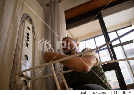 Happy man setting up an ironing board at home Happy man setting up an ironing board at home 133613609
