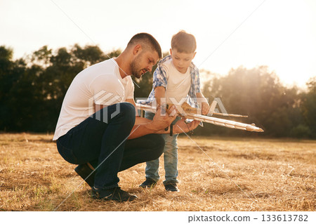 The problem, fixing it. Father and son are with wooden toy plane on the field 133613782