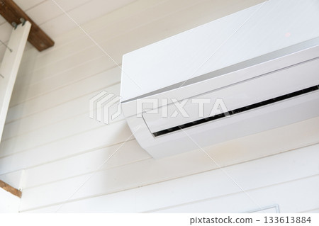 Air conditioner installed on white wall in bright interior of wooden house Air conditioner installed on white wall in bright interior of wooden house 133613884