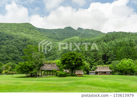 在西湖野鳥森林公園廣闊的草坪上，矗立著一座古樸的茅草屋頂涼亭，背景則是原始森林。 133613979