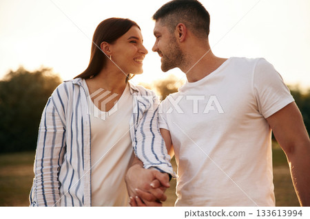 Looking at each other. Beautiful couple is in love, standing on the field together Looking at each other. Beautiful couple is in love, standing on the field together 133613994