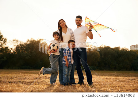 Man is holding kite in hand. Family of father, mother, daughter and son that are standing in the field Man is holding kite in hand. Family of father, mother, daughter and son that are standing in the field 133614008