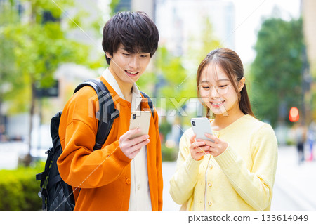 Young men and women looking at smartphones in the city Young men and women looking at smartphones in the city 133614049