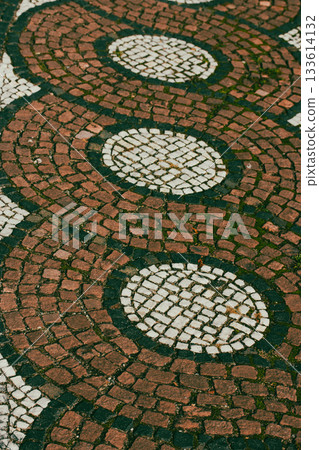 This eye-level shot captures a patterned cobblestone pavement, featuring concentric circles and flowing lines for an intriguing design Circular design 133614132