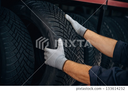 Close up view, taking the tire. Man worker is maintenance station with wheels Close up view, taking the tire. Man worker is maintenance station with wheels 133614232