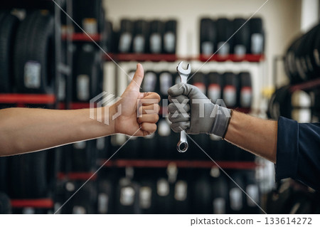 Automotive concept, repair, two male hands, one is holding wrench, ready to repair, another one with thumb up 133614272