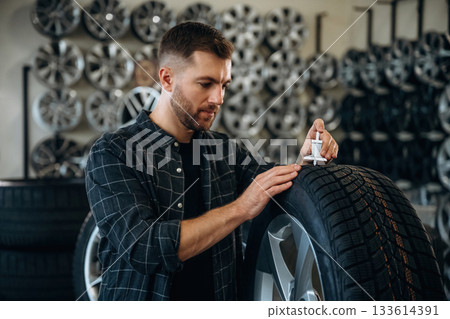 Ready for install, perfect measure, with tool. Man worker is maintenance station with tires, wheels 133614391