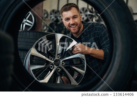 Brand new disk. Man worker is maintenance station with tires, wheels Brand new disk. Man worker is maintenance station with tires, wheels 133614406
