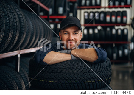 Inside of the wheels, having fun. Man worker is maintenance station with tires 133614428