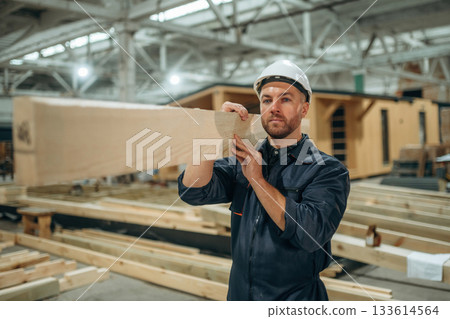 Wooden plank in hands. Male builder is at construction of house Wooden plank in hands. Male builder is at construction of house 133614564