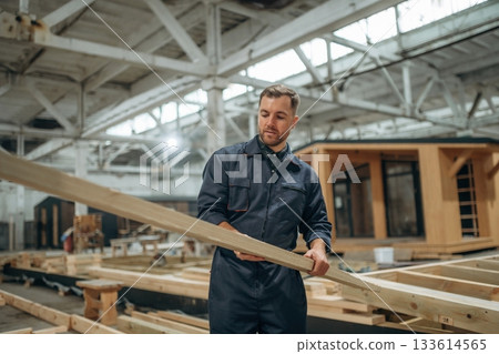 Wooden plank in hands. Male builder is at construction of house Wooden plank in hands. Male builder is at construction of house 133614565
