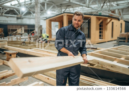 Wooden plank in hands. Male builder is at construction of house Wooden plank in hands. Male builder is at construction of house 133614566