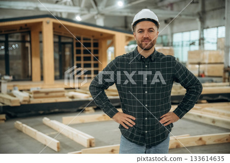 In white helmet. Male builder is at construction of wooden house In white helmet. Male builder is at construction of wooden house 133614635