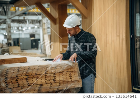In white helmet. Male builder is at construction of wooden house In white helmet. Male builder is at construction of wooden house 133614641