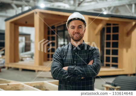 Cheerful facial expression. Male builder is at construction of wooden house 133614648