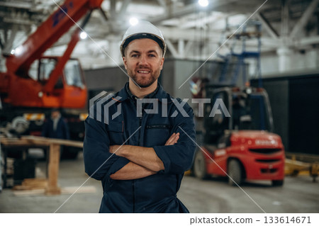 Front view, standing. Male worker is in the modern warehouse or manufacturing company Front view, standing. Male worker is in the modern warehouse or manufacturing company 133614671