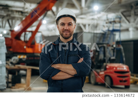 Front view, standing. Male worker is in the modern warehouse or manufacturing company Front view, standing. Male worker is in the modern warehouse or manufacturing company 133614672