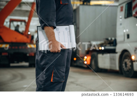 Documents in notepad. Male worker is in the modern warehouse or manufacturing company Documents in notepad. Male worker is in the modern warehouse or manufacturing company 133614693
