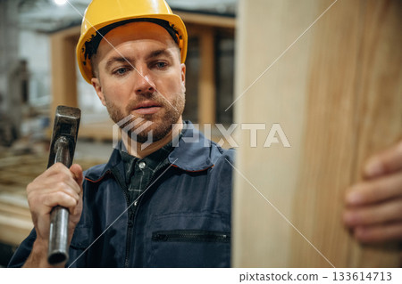 Plank and a hammer. Male builder is at construction of wooden house Plank and a hammer. Male builder is at construction of wooden house 133614713