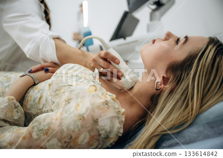 Side view. Woman is lying down and undergoing ultrasonic test of the thyroid gland Side view. Woman is lying down and undergoing ultrasonic test of the thyroid gland 133614842