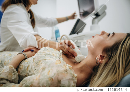 Side view. Woman is lying down and undergoing ultrasonic test of the thyroid gland Side view. Woman is lying down and undergoing ultrasonic test of the thyroid gland 133614844