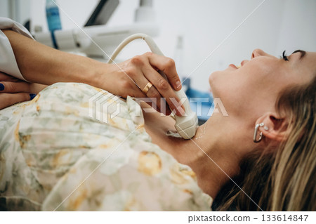 Side view. Woman is lying down and undergoing ultrasonic test of the thyroid gland 133614847