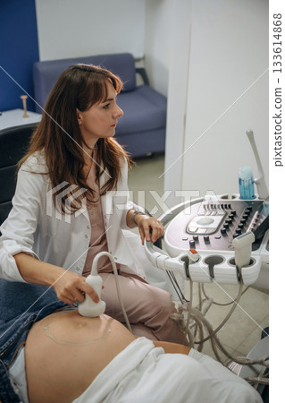 Scanning in progress. Pregnant woman undergoing ultrasound test Scanning in progress. Pregnant woman undergoing ultrasound test 133614868