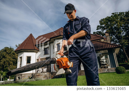 Using leaf blower. Professional gardener is on the lawn Using leaf blower. Professional gardener is on the lawn 133615085